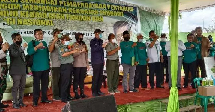 Sekelompok orang, sebagian berkaus hijau dan sebagian berseragam, berdiri berjajar dengan tangan terkepal di panggung berkarpet merah, di depan spanduk bertuliskan "Semangat Pemberdayaan Pertanian" dan "Kedaulatan Pangan".